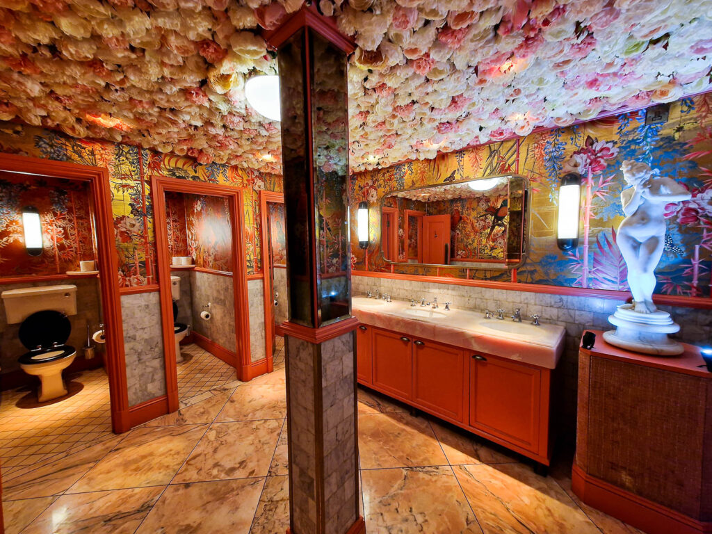 The ivy Winchester female toilets with beautiful decoration of pink and white flowers on the ceiling, flower wallpaper and a statue of a lady on a table with lights at the bottom to glow the statue up