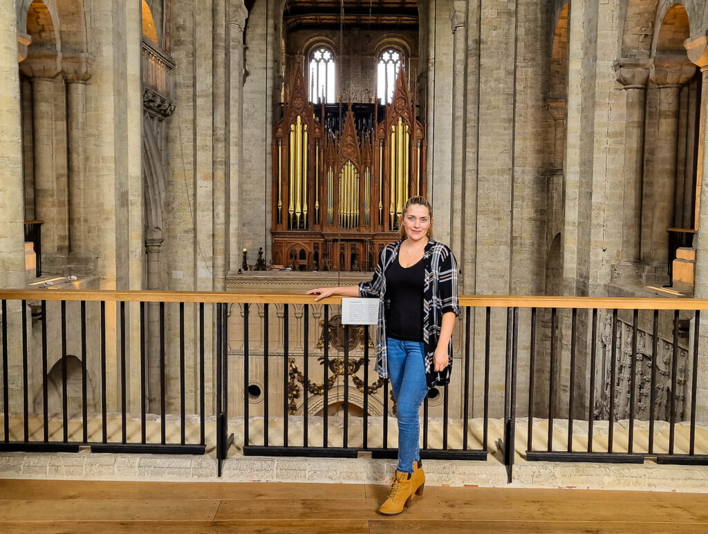 Kay standing in the Winchester Cathedral with a piano organ in the background