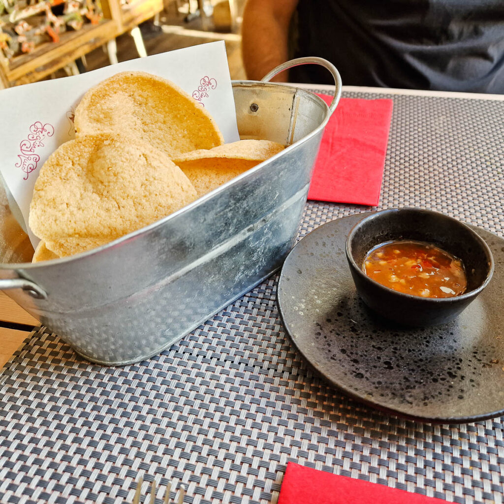 Thai prawn crackers in a silver bucket with homemade sweet chilli sauce in a black pot