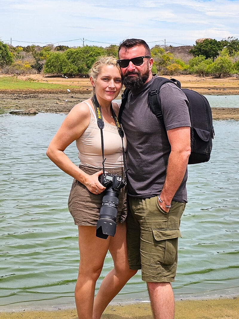 Luke and Kay from Flawless Journeys standing next to a lake holding her camera.
