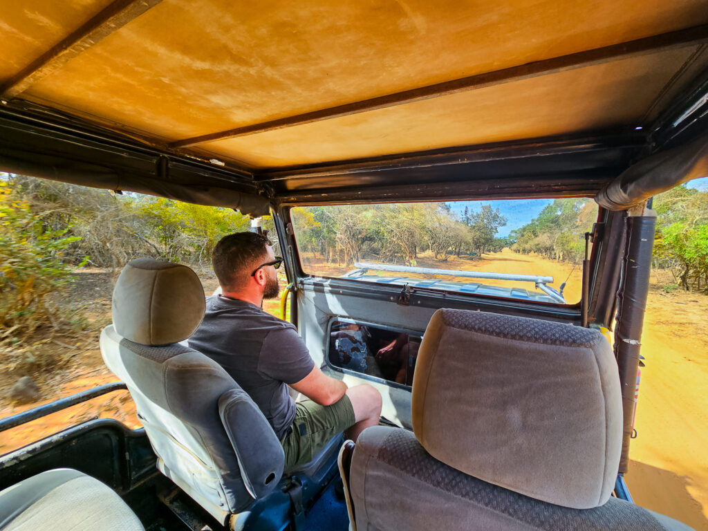 Luke sitting in the front of safari jeep driving on the roads in Yala National Park Sri Lanka