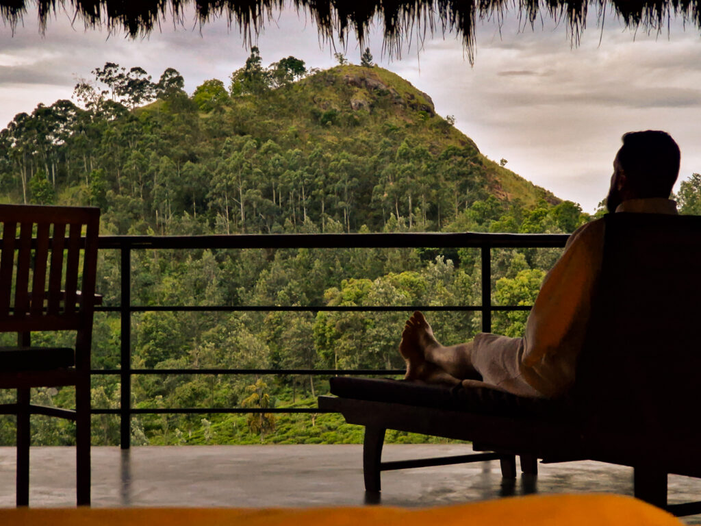 Luke sitting on a sun lounger in his robe on the room balcony looking over the Little Adams Peak in Ella Sri Lanka