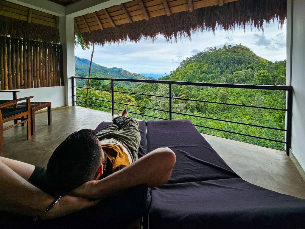 Luke laying on a sun lounger on the room balcony looking over the Little Adams Peak in Ella Sri Lanka