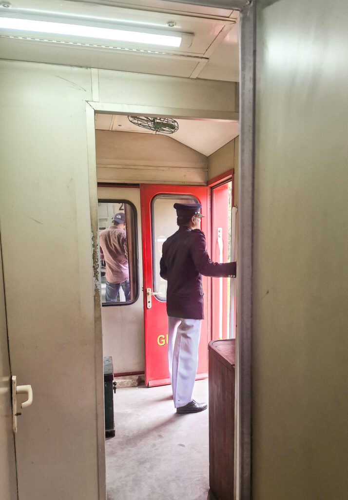 Sri Lanka Train from Ella train guard standing in an open door way of the train